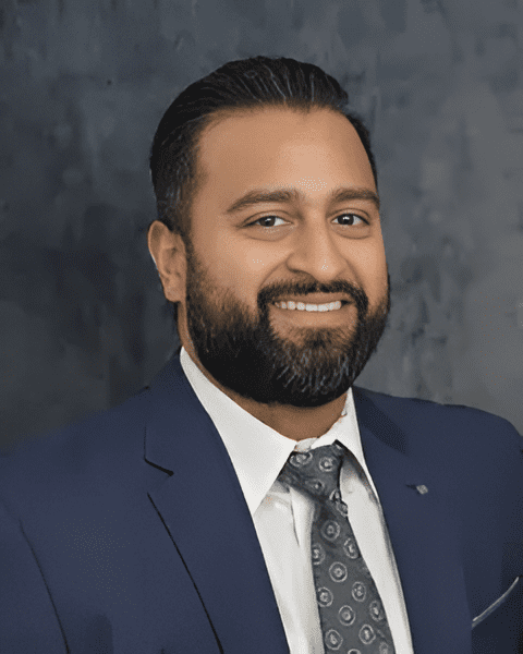 Expert orthopedic rehabilitation specialist Dr. Raj Desai smiling in a navy suit and silver tie