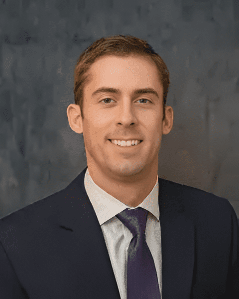 Expert orthopedic hand and wrist surgeon Dr. Brent Pickrell smiling in a navy suit and purple tie