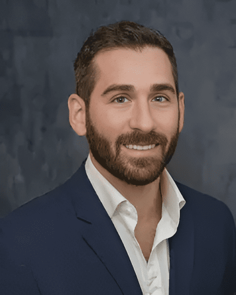 Expert orthopedic sports medicine specialist Dr. Michael Perrone smiling in a blue suit