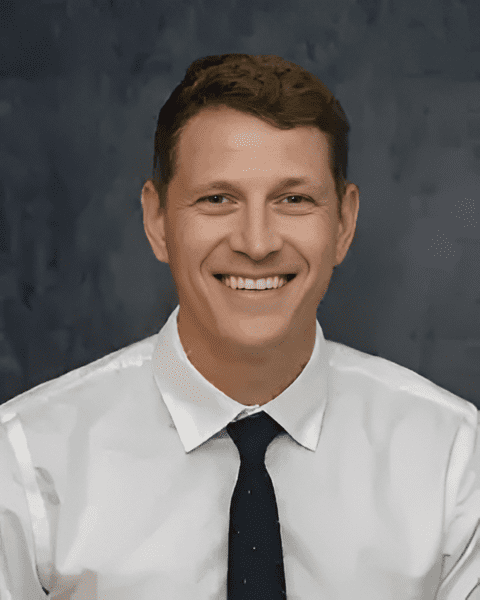 Expert orthopedic surgeon Dr. Erik Dworsky smiling in a white dress shirt and navy tie