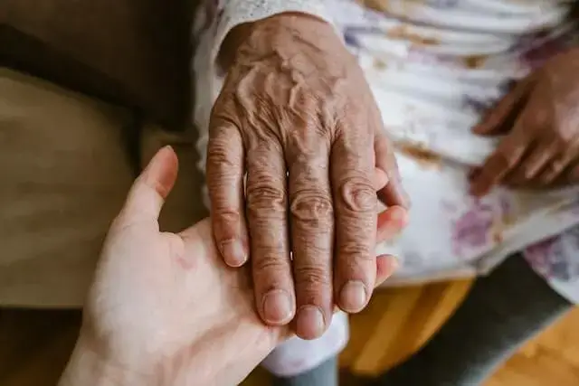 Caregiver holds hand of elderly patient