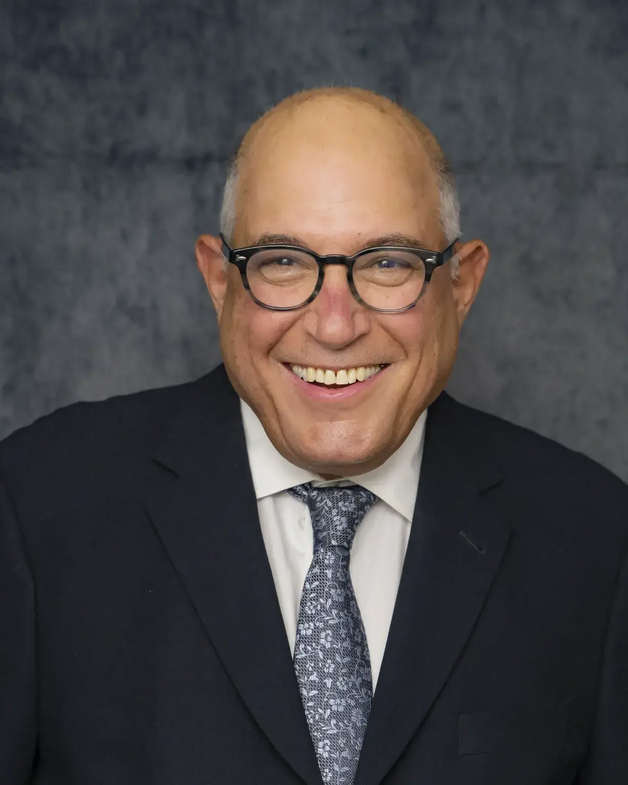 Podiatrist Dr. Michael Marcus in a navy suit, blue patterned tie, and glasses