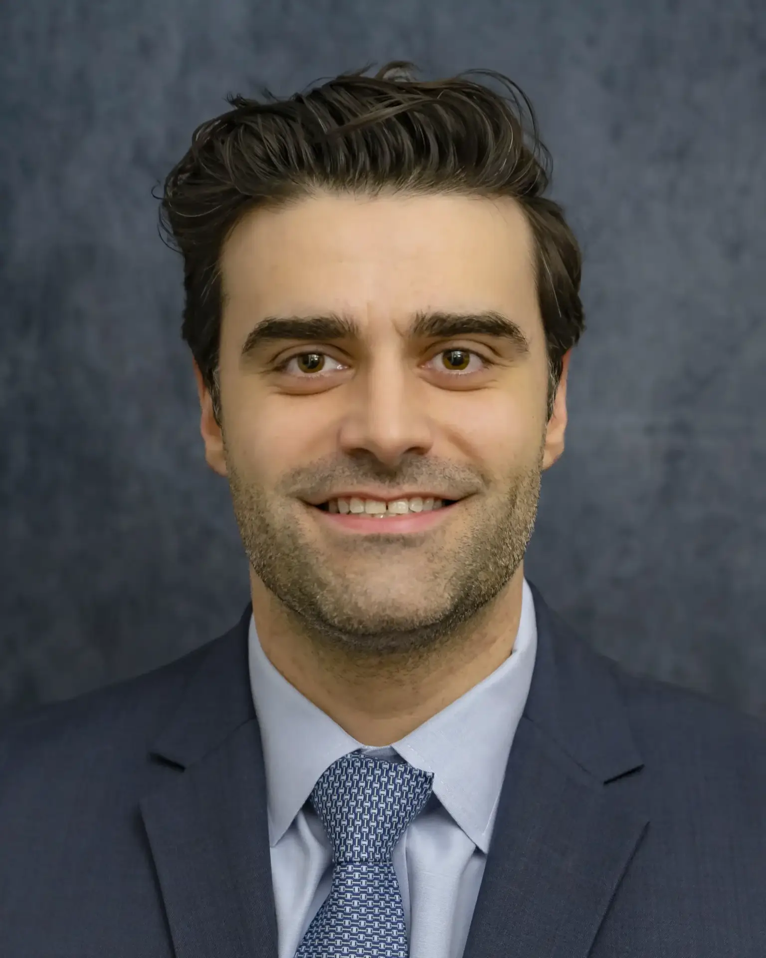 Expert orthopedic surgeon Dr. Sevag A. Bastian smiling in a blue suit and tie