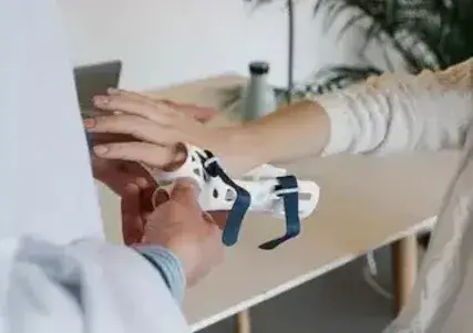 Orthopedist fitting a patient with a plastic brace that goes over their fingers