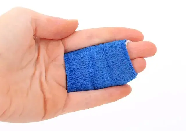 Close up of a hand with blue bandage tape wrapped around the the middle and ring finger