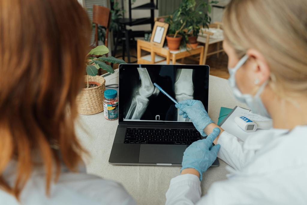 Two orthopedists reviewing scans of a patient on their computer