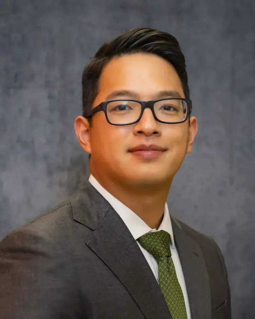 Podiatrist Dr. Danny Wang in a suit, green patterned tie and black glasses